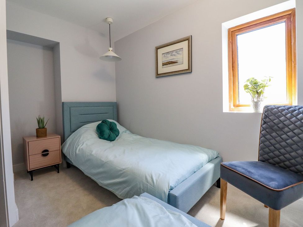 A bedroom with a bed, chair, and window at Trefin in Cemaes Bay