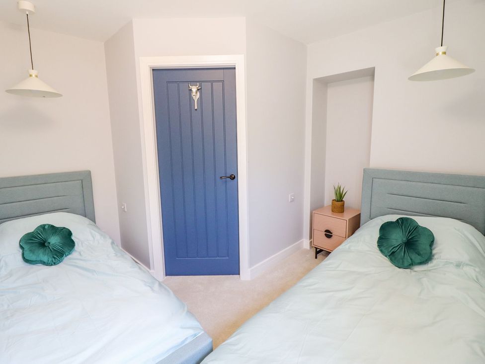 A bedroom with two single beds and a blue door at Trefin in Cemaes Bay