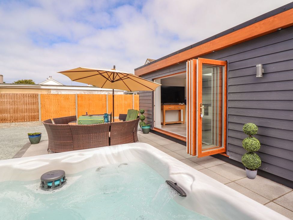 An outdoor area with a hot tub and seating at Trefin in Cemaes Bay
