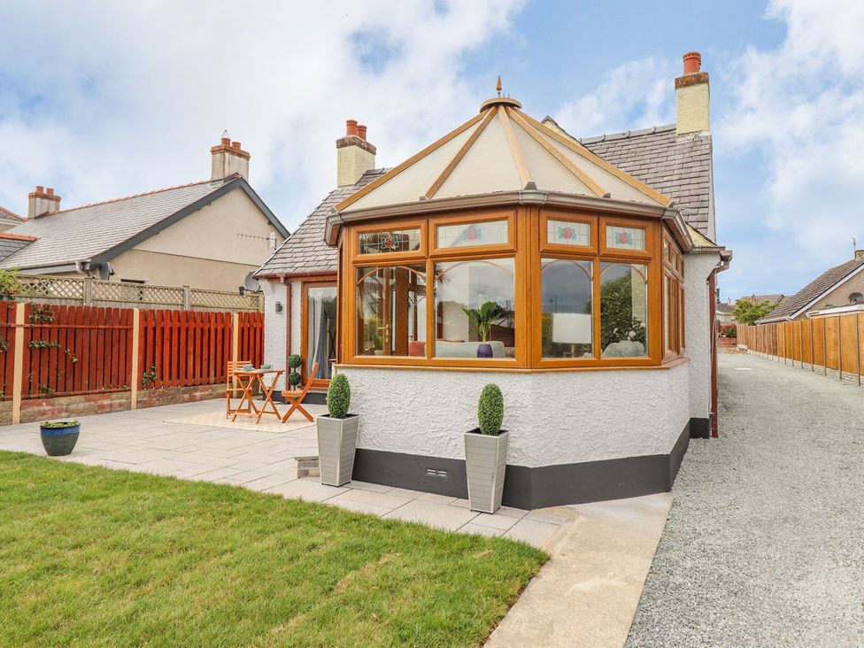 A conservatory with a table and chairs at Trefin in Cemaes Bay