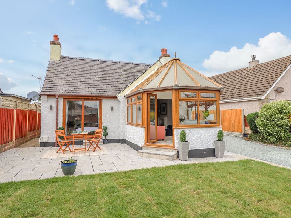 A garden with a patio set and a conservatory at Trefin in Cemaes Bay