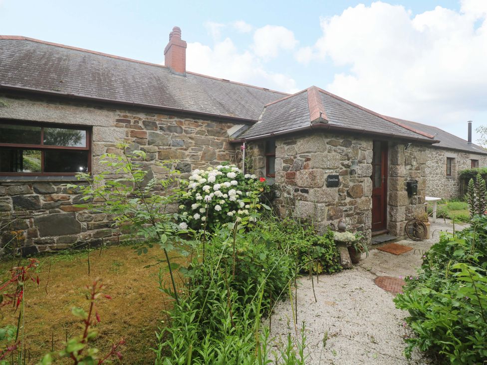 An outdoor view of a stone cottage entrance with garden at Swallow Cottage in Helston