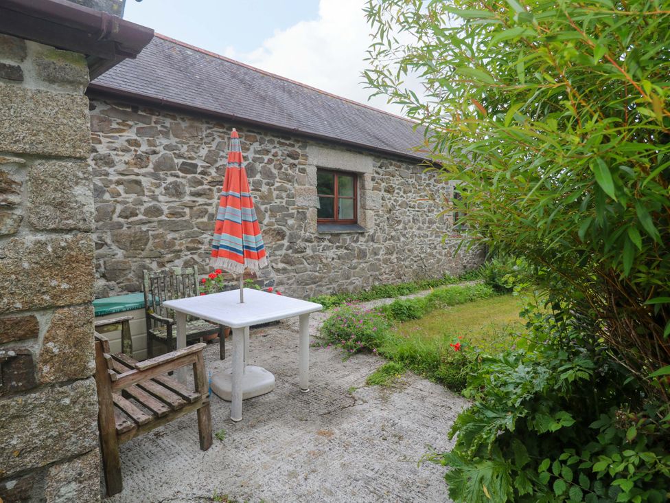 A garden area with a table and chairs at Swallow Cottage Helston