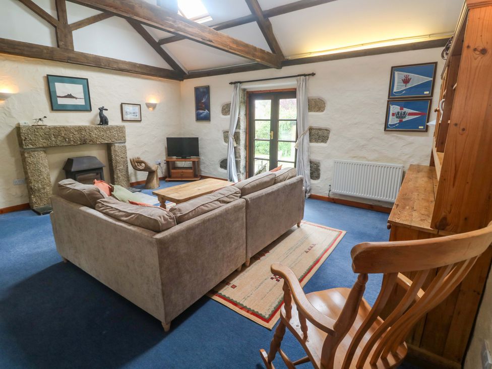 A living room with a sofa and TV at Swallow Cottage in Helston