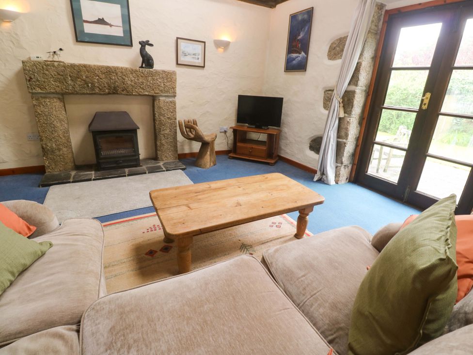 A living room with a fireplace and television at Swallow Cottage Helston
