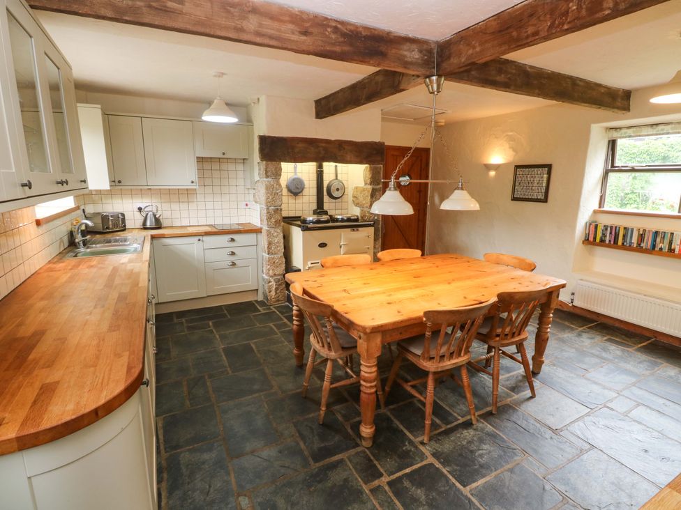 A kitchen with a table and chairs at Swallow Cottage in Helston