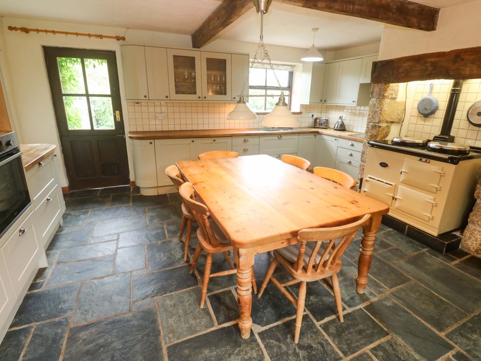 A kitchen with a wooden table and chairs at Swallow Cottage in Helston