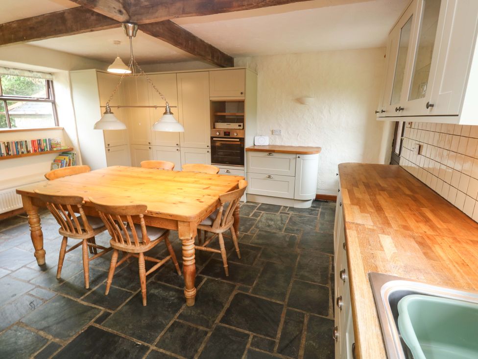 A kitchen with a dining table and chairs at Swallow Cottage in Helston