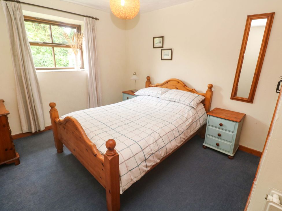 A bedroom with a bed and a nightstand at Swallow Cottage in Helston