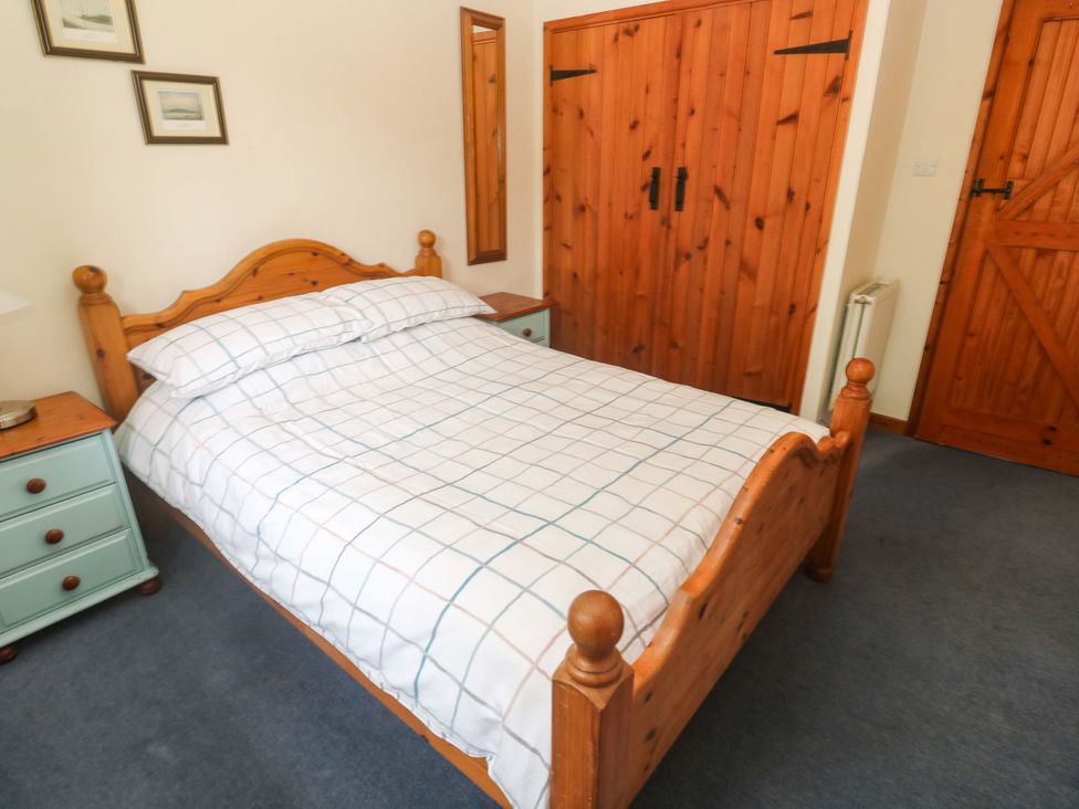 A bedroom with a bed and bedside table at Swallow Cottage in Helston