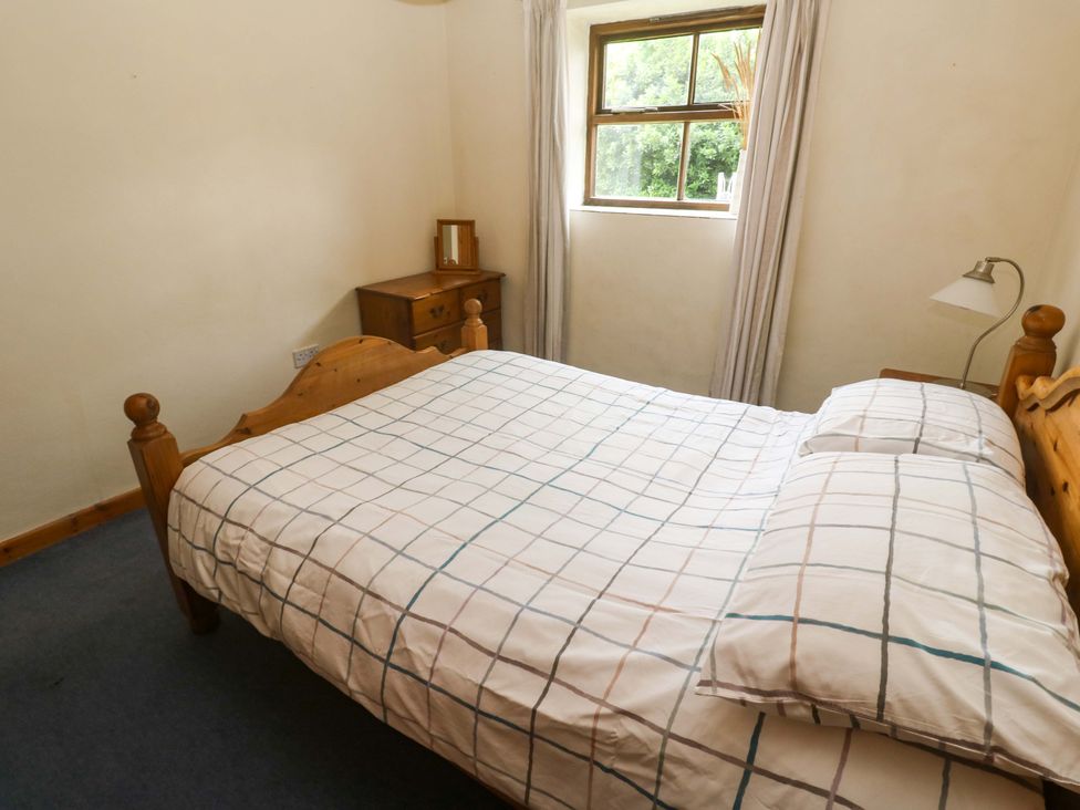 A bedroom with a bed and window at Swallow Cottage Helston