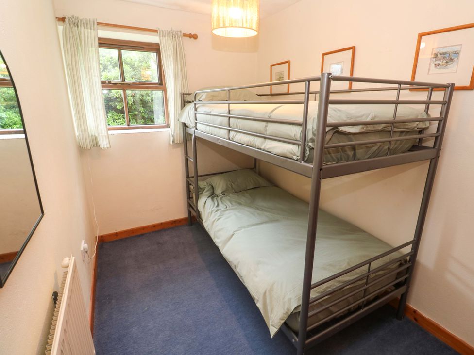 A bedroom with a bunk bed and a window at Swallow Cottage in Helston