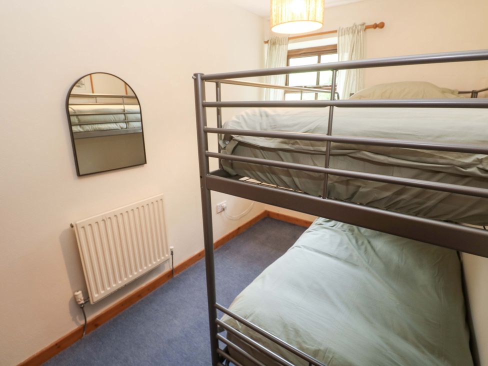 A bunk bed with green bedding in a bedroom at Swallow Cottage in Helston