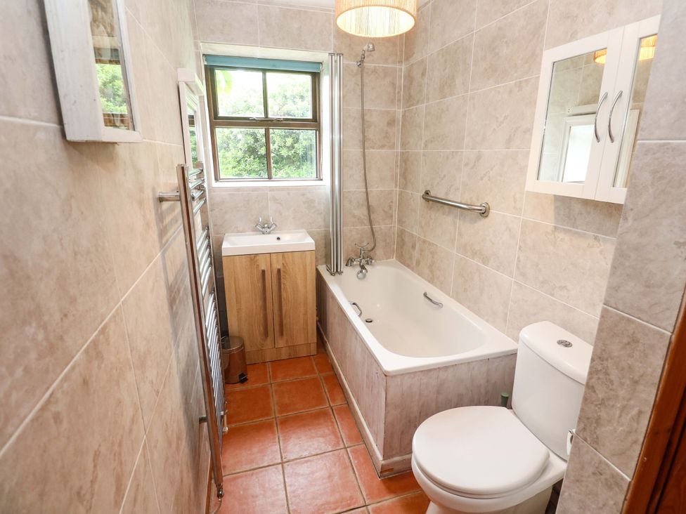 A bathroom with a bathtub, sink, and toilet at Swallow Cottage in Helston