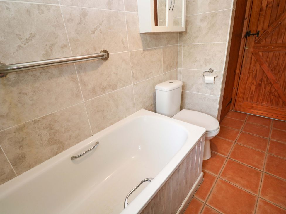 A bathroom with a bathtub, toilet, and sink at Swallow Cottage in Helston