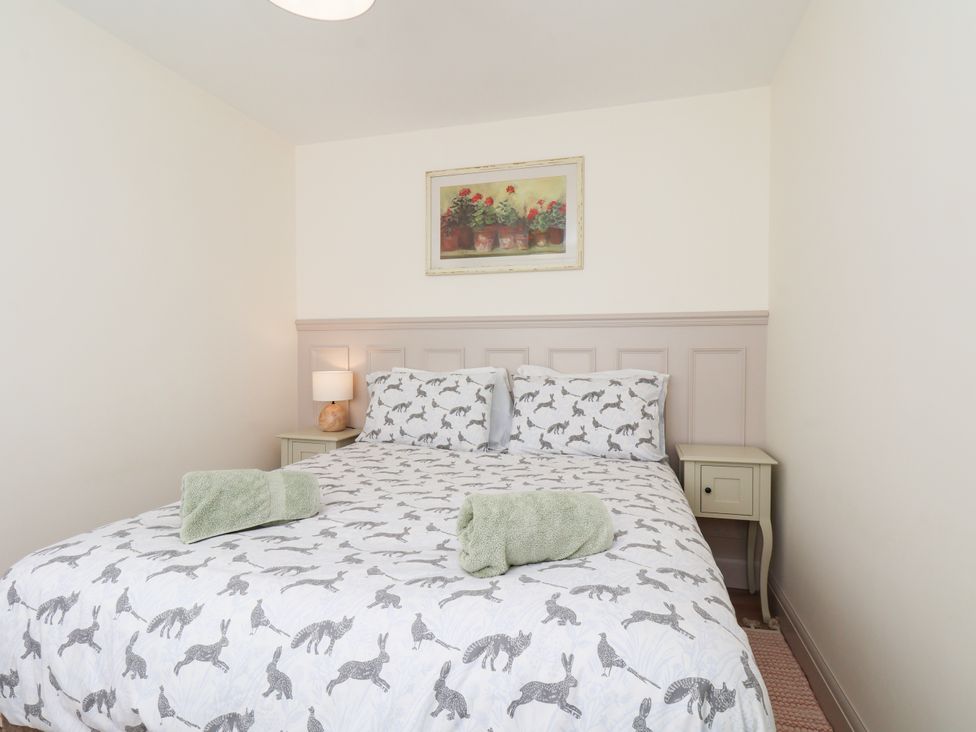 A bedroom with a bed and a painting at Badger Cottage in Driffield
