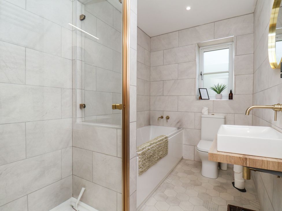 A bathroom with a shower, bathtub, toilet, and sink at Badger Cottage in Driffield