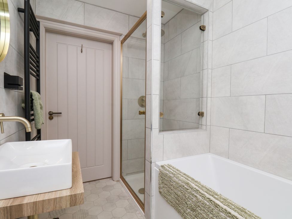 A bathroom with a shower and bath tub at Badger Cottage in Driffield