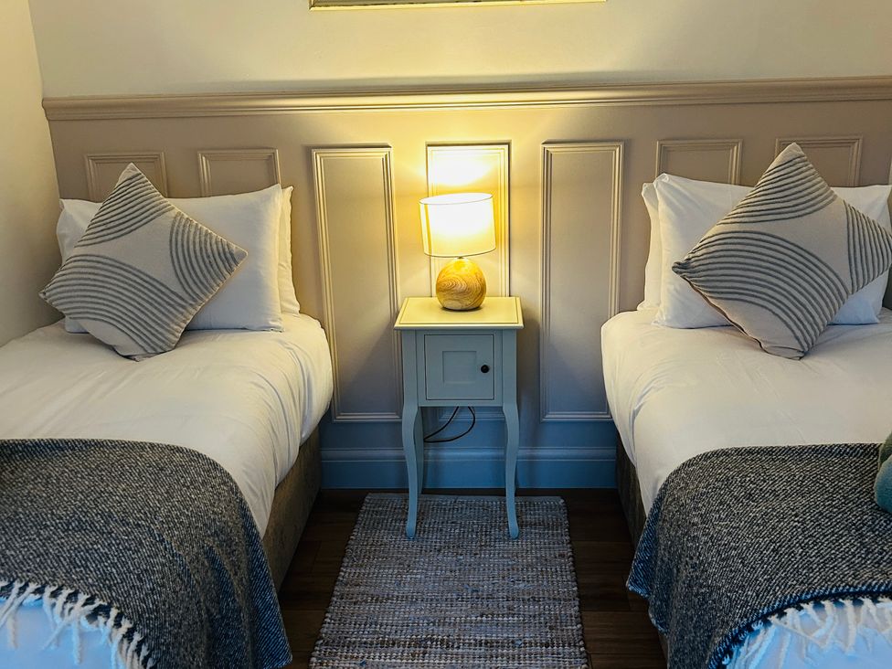 A bedroom with two single beds and a lamp on a side table at Badger Cottage in Wold Newton