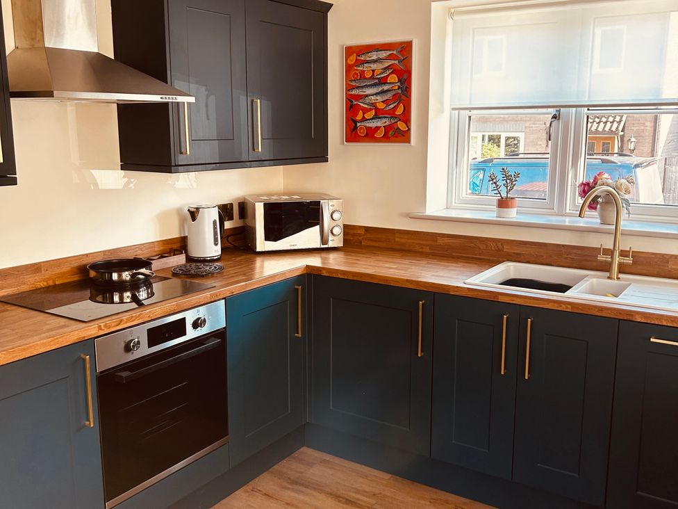 A kitchen with appliances and a window at Badger Cottage Wold Newton