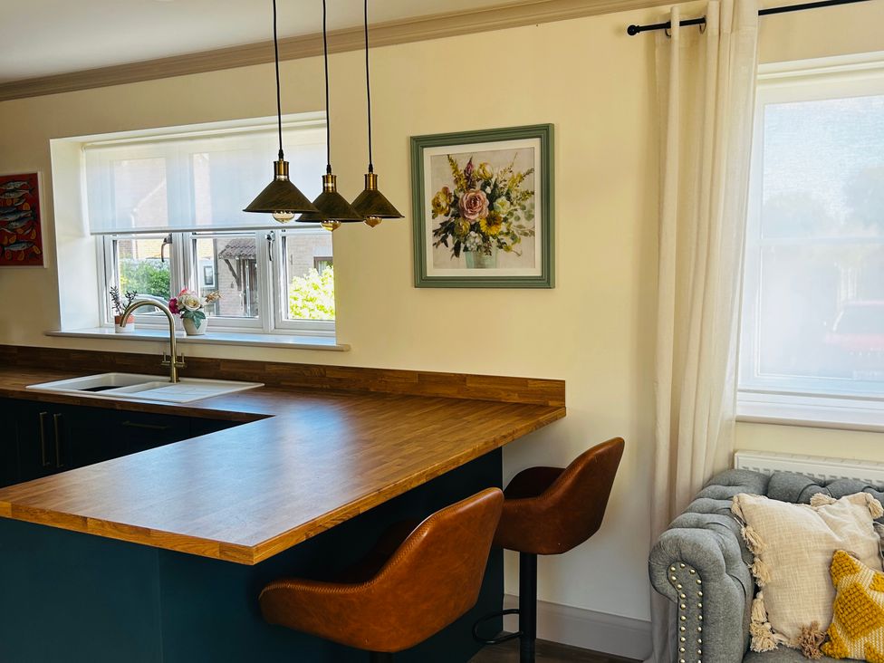 A kitchen with a sink and bar stools at Badger Cottage in Wold Newton