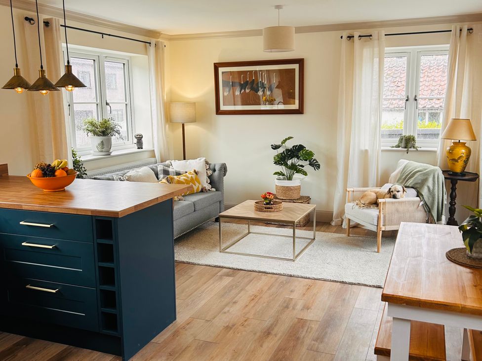 A living room with a sofa, coffee table, and dog at Badger Cottage in Wold Newton