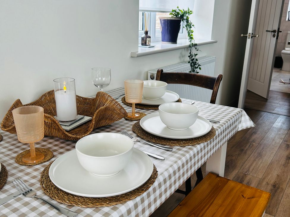 A dining table set with plates and bowls at Badger Cottage in Wold Newton