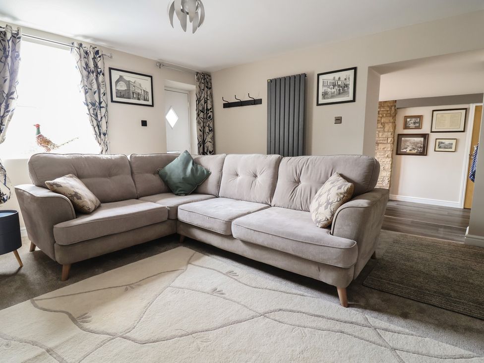 A living room with a sofa and framed pictures at The Old Shady Oak Cottage in High Peak