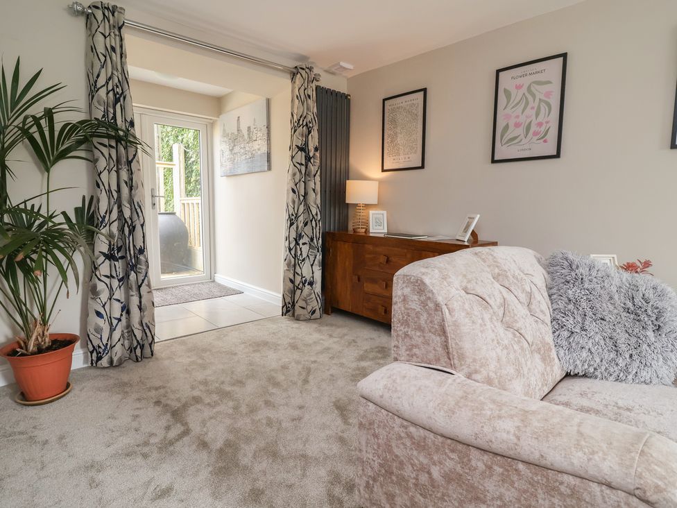 A living room with a sofa and a door leading outside at The Old Shady Oak Cottage High Peak