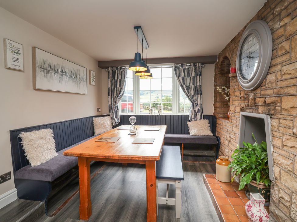 A dining room with a table and benches at The Old Shady Oak Cottage in High Peak