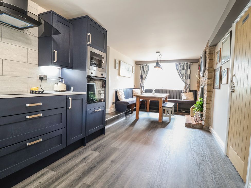 A kitchen and dining area with cabinets and table at The Old Shady Oak Cottage in High Peak