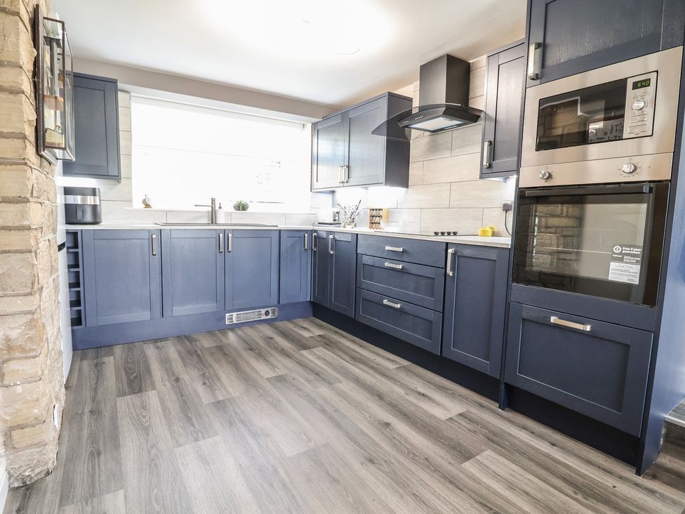 A kitchen with dark cabinets and countertop at The Old Shady Oak Cottage, High Peak