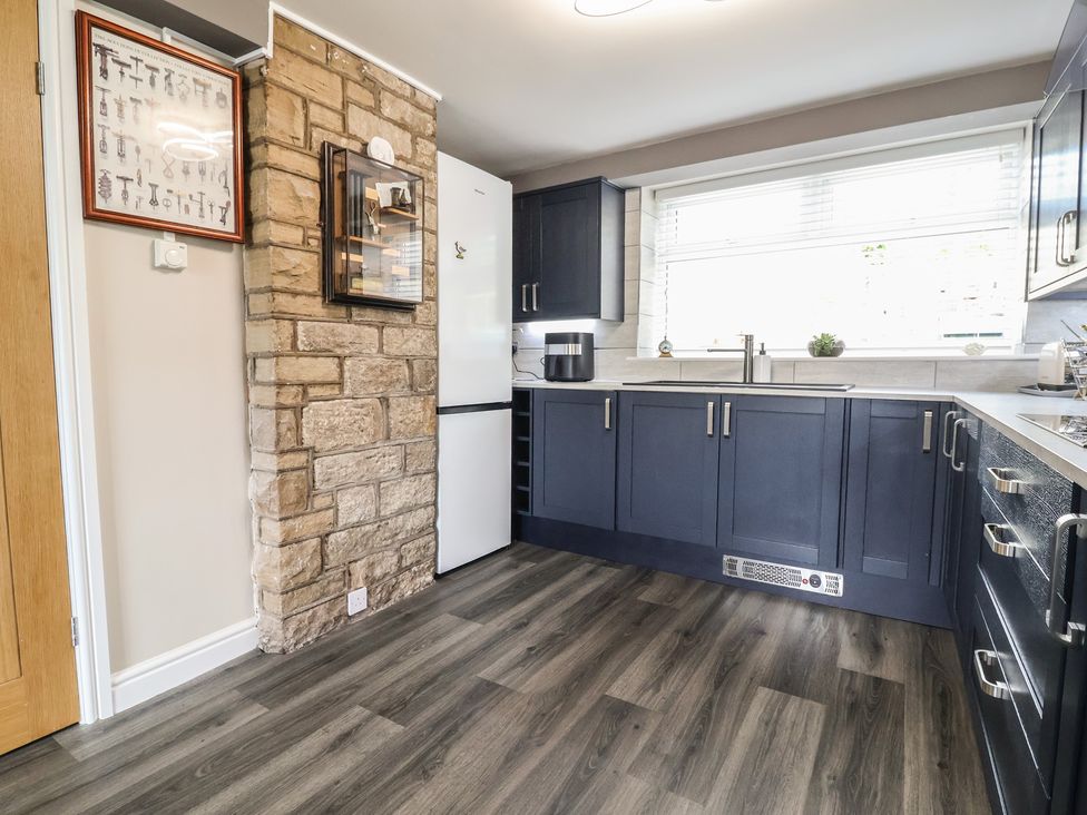A kitchen with cabinets and a fridge at The Old Shady Oak Cottage in High Peak