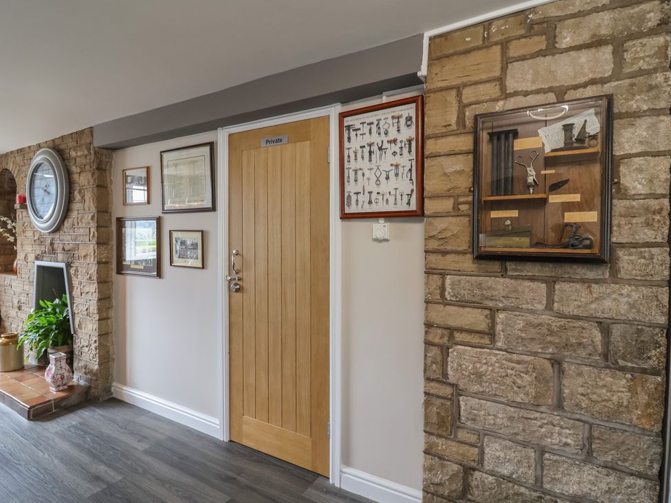 A hallway with a door and framed art at The Old Shady Oak Cottage in High Peak
