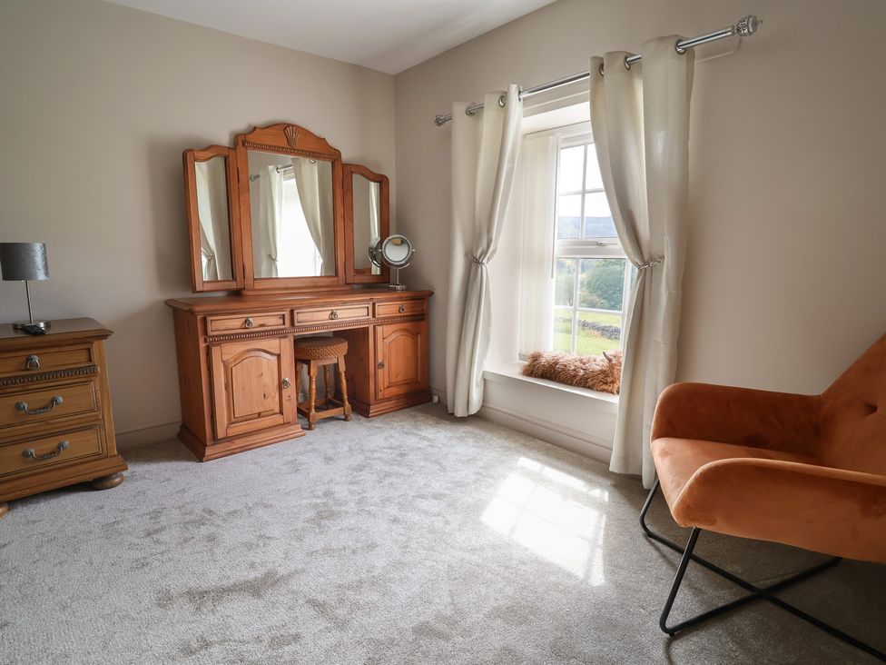 A bedroom with a dressing table and an armchair at The Old Shady Oak Cottage High Peak