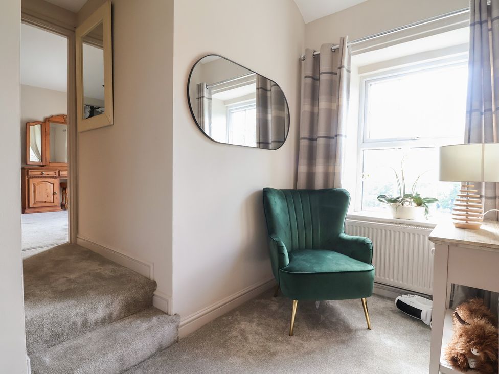 A hallway with a green armchair and mirror at The Old Shady Oak Cottage High Peak