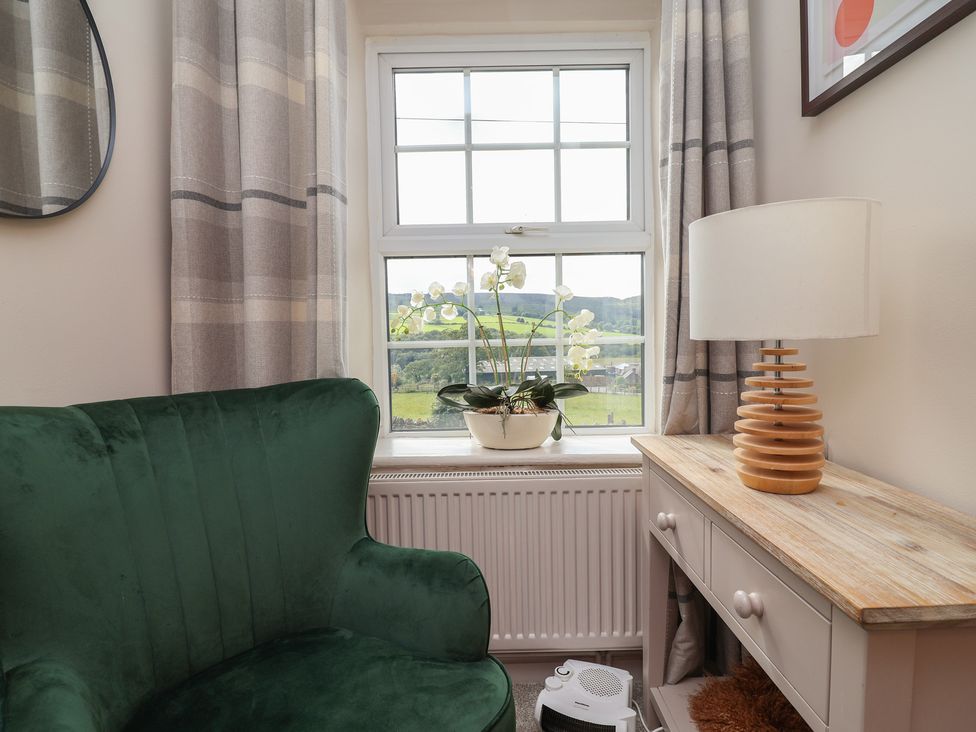 A sitting room with an armchair and a window at The Old Shady Oak Cottage in High Peak
