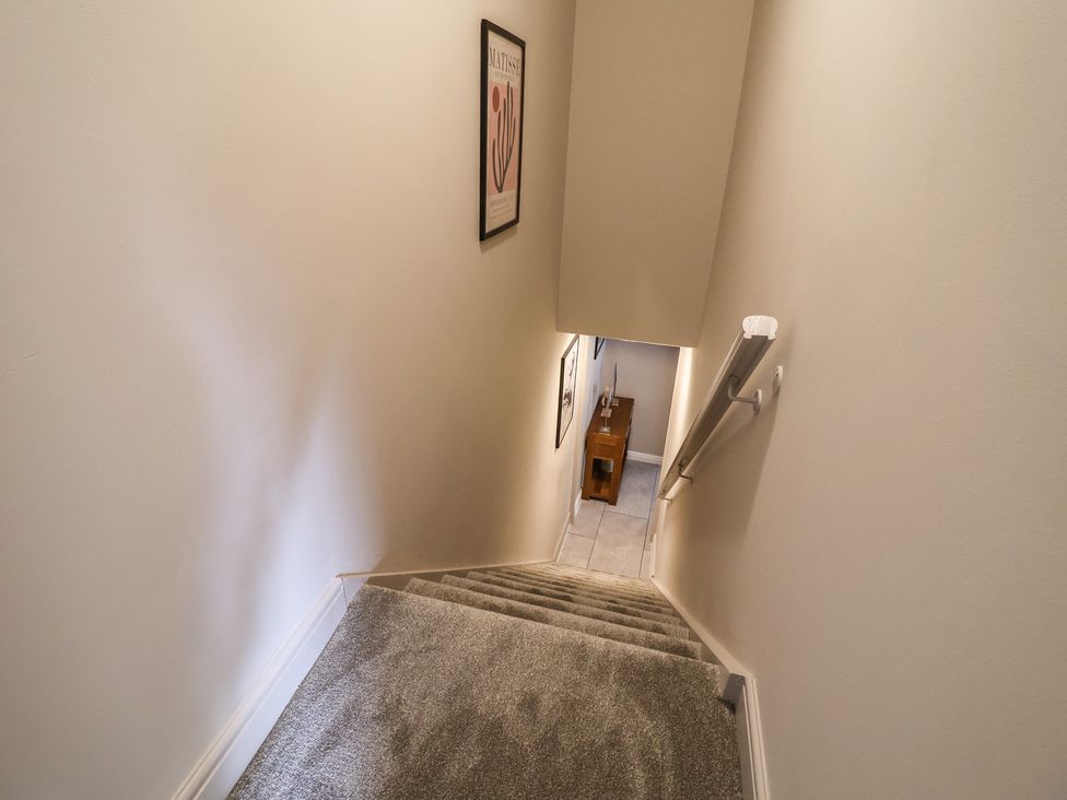 A staircase with a handrail and artwork at The Old Shady Oak Cottage High Peak