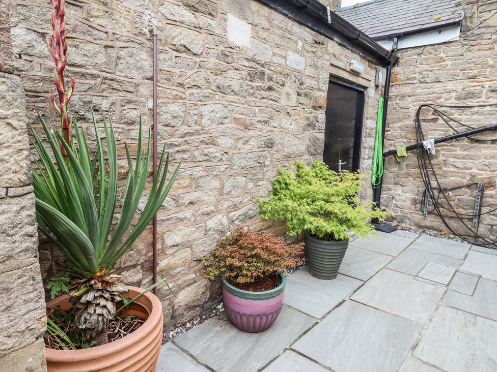 A garden area with potted plants and a stone wall at The Old Shady Oak Cottage in High Peak