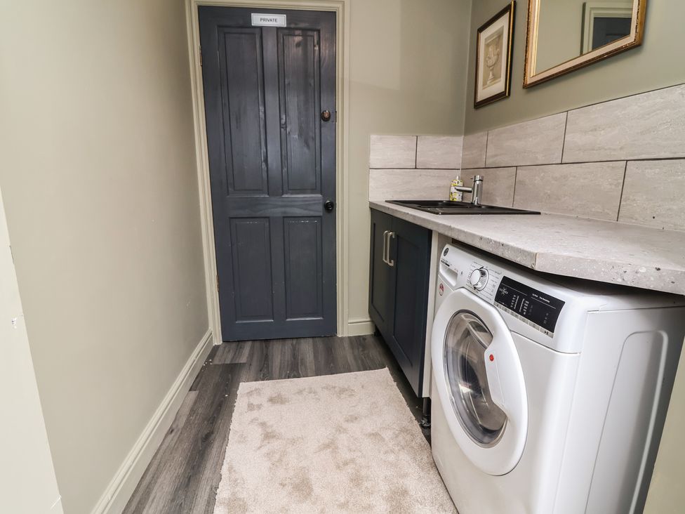 A laundry room featuring a washing machine and a sink at The Old Shady Oak Cottage in High Peak
