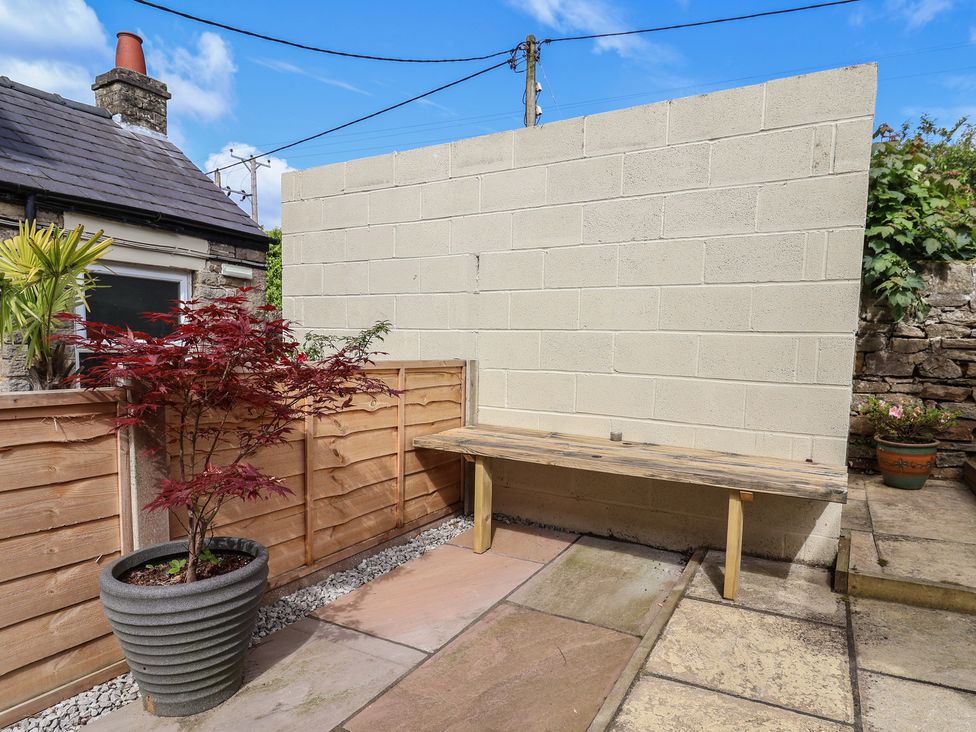 A garden with a wooden bench and plants at The Old Shady Oak Cottage in High Peak