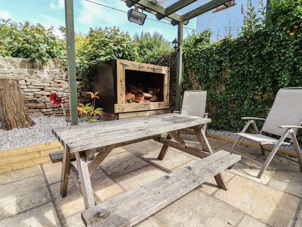 A garden with a wooden table and chairs at The Old Shady Oak Cottage High Peak