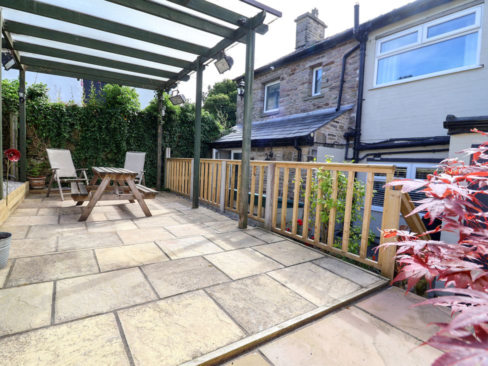 A patio with a table and chairs under a pergola at The Old Shady Oak Cottage High Peak