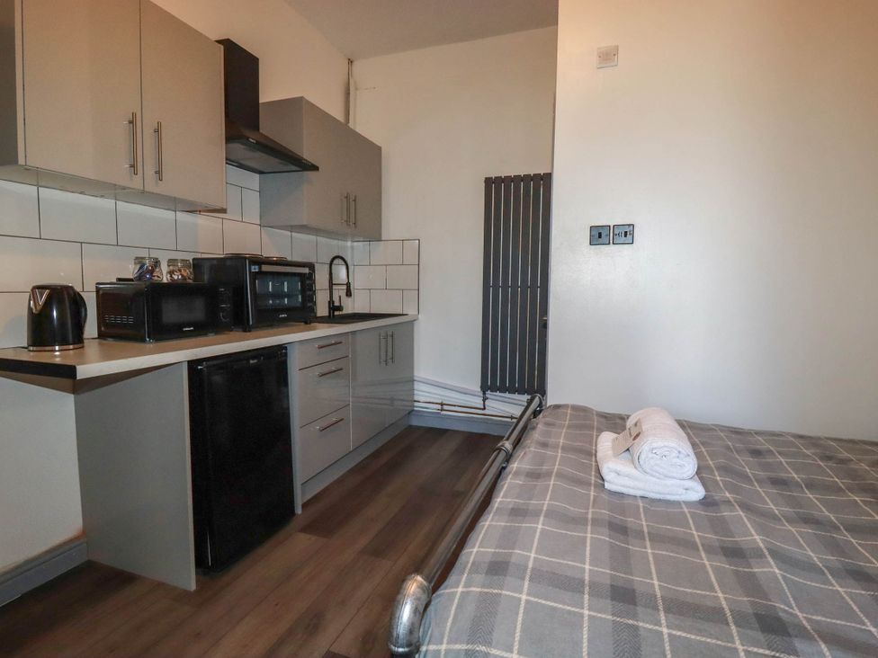 A kitchen area with modern appliances and a bed in Studio Room No.2 Newquay