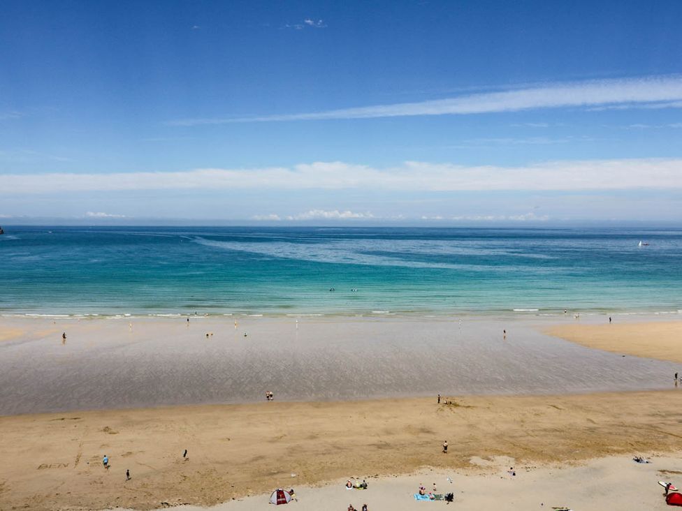 A beach with people walking on sand and ocean at Shoreline Studio No.7 in Newquay