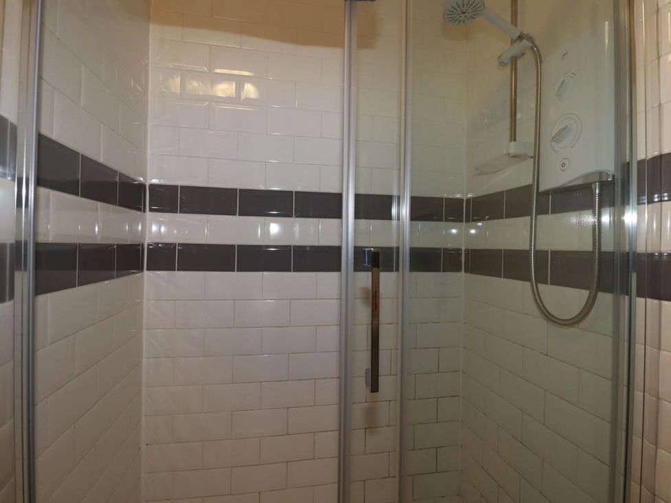 A shower with tiles and controls at Shoreline Studio No.7, Newquay