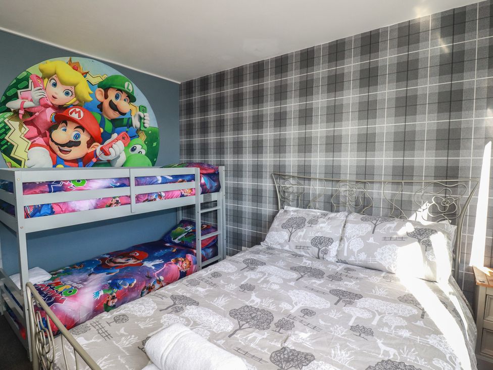 A bedroom with a bunk bed and double bed at Shoreline Apartment No.8, Newquay