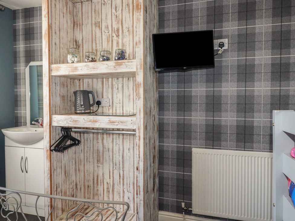 A bedroom with a shelf and tv at Shoreline Apartment No.8 in Newquay