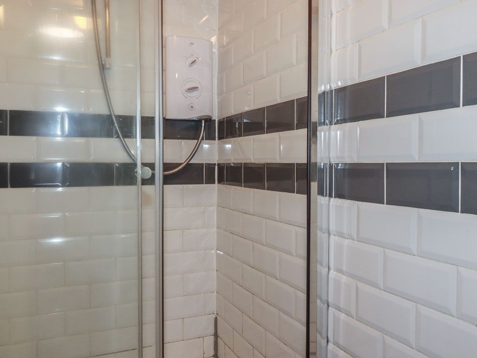 A shower with tiles and controls at Shoreline Apartment No.8 in Newquay