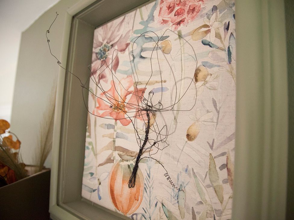 A decorative art piece featuring wire and floral fabric at Snug Cottage in Honley